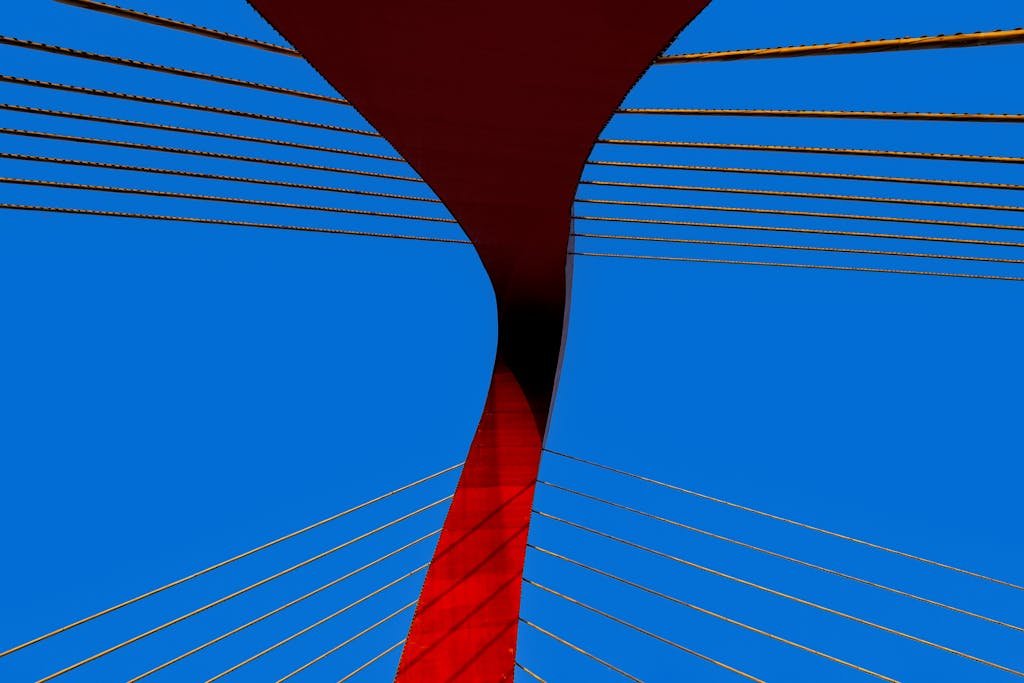 A striking modern bridge with red and blue colors and abstract lines against a clear sky.