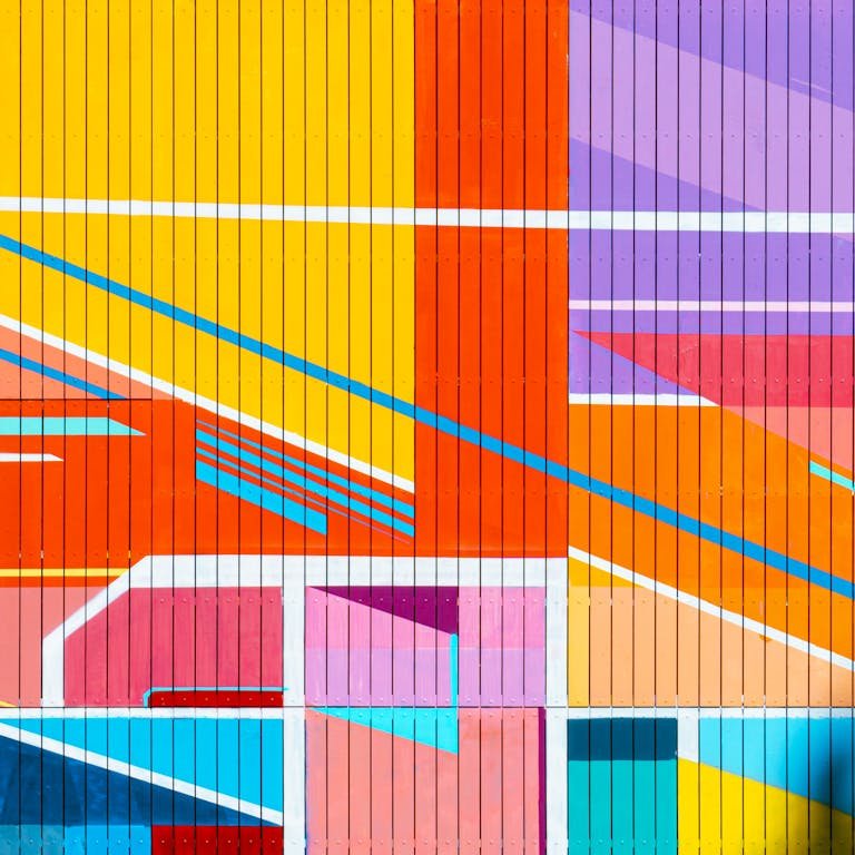 Vibrant geometric mural art with bright colors and patterns on a wooden wall in Barcelona.