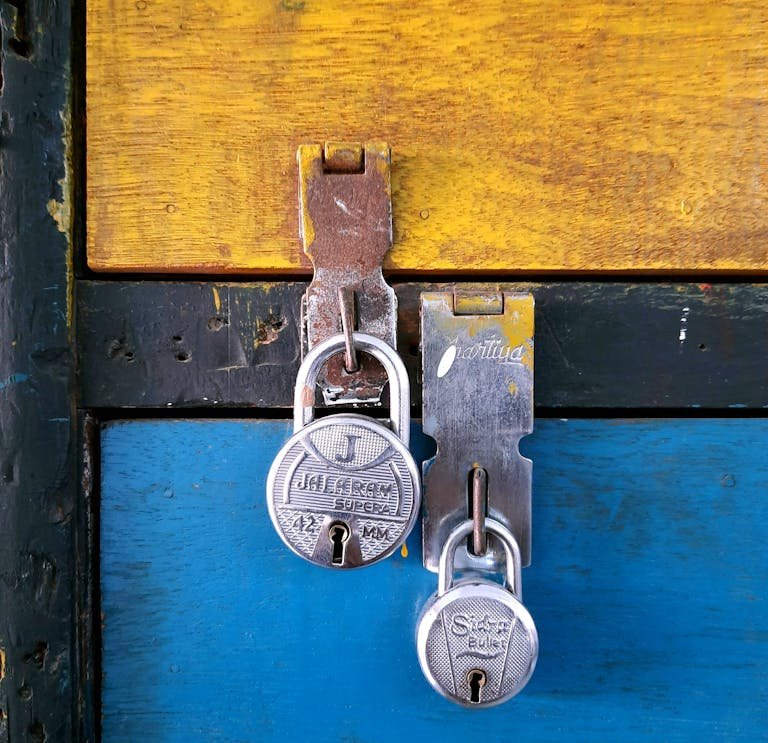 Close-up of two silver padlocks securing a colorful painted wooden chest, emphasizing security and protection.